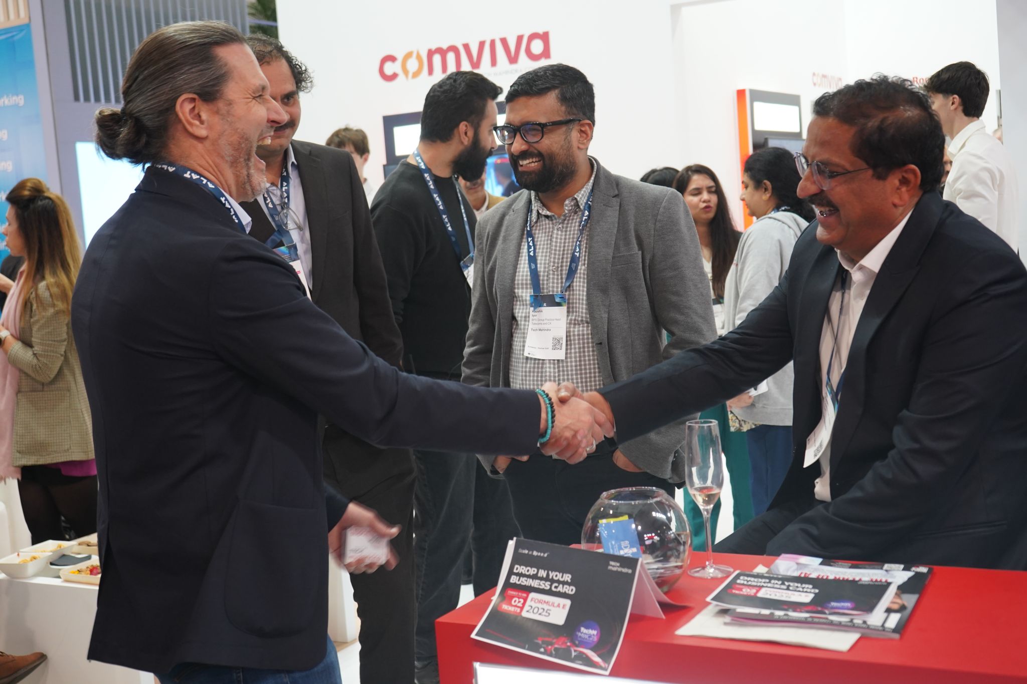 Booth staff clustered around an interactive demonstration, forming the first ring of a trade show crowd